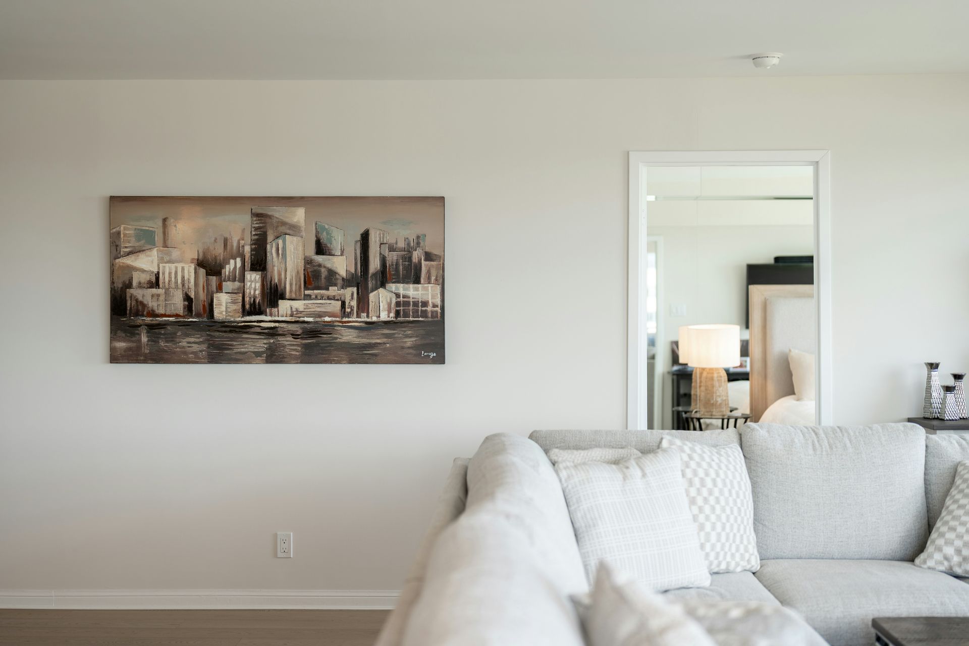 Contemporary living room featuring cityscape artwork and a light sofa